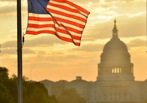 United States Capitol building silhouette and US flag at sunrise - Washington DC